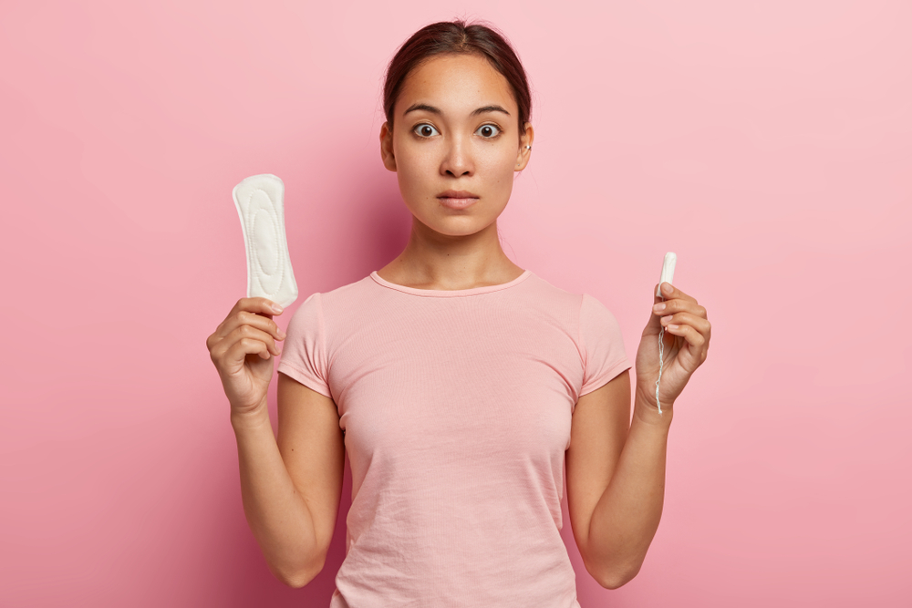 Woman holding tampon and pad. Toxic shock syndrome can occur from bacteria entering your body through tampons.