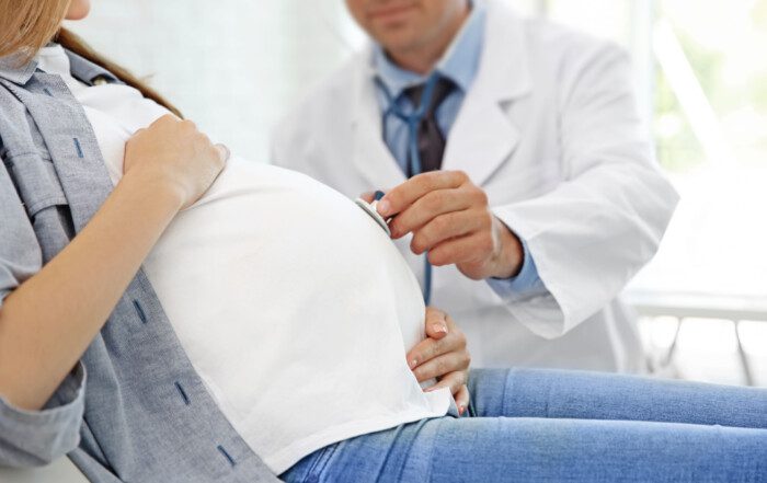 Pregnant woman receiving prenatal care from a healthcare professional